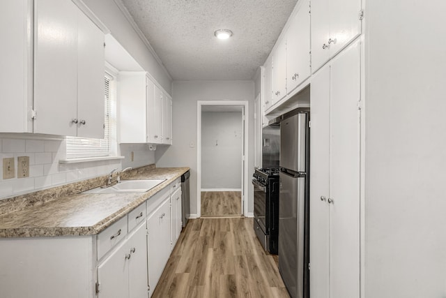 kitchen with sink, white cabinetry, backsplash, stainless steel appliances, and a textured ceiling