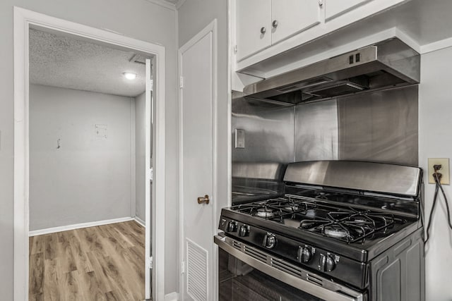 kitchen with light hardwood / wood-style flooring, gas stove, white cabinets, a textured ceiling, and exhaust hood