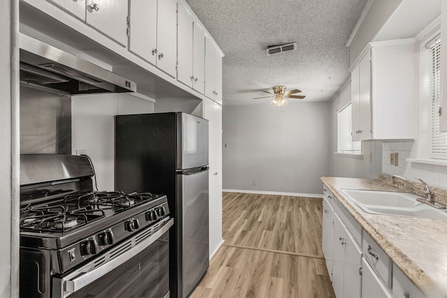 kitchen with a textured ceiling, sink, range with gas cooktop, and white cabinets