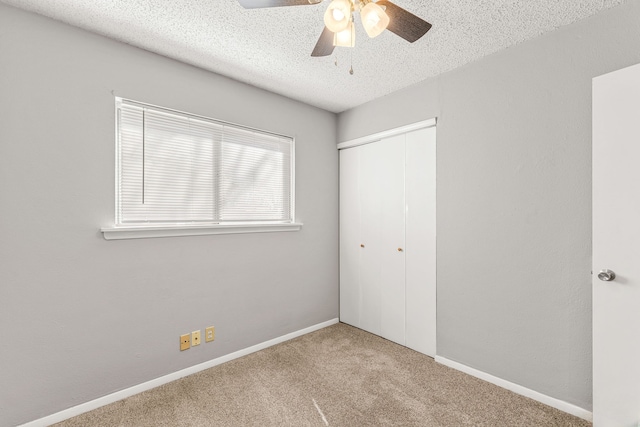 unfurnished bedroom featuring ceiling fan, light colored carpet, a closet, and a textured ceiling