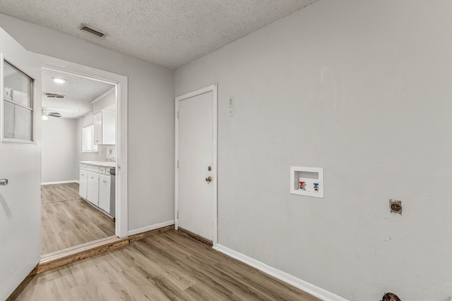 laundry room with washer hookup, electric dryer hookup, a textured ceiling, and light wood-type flooring