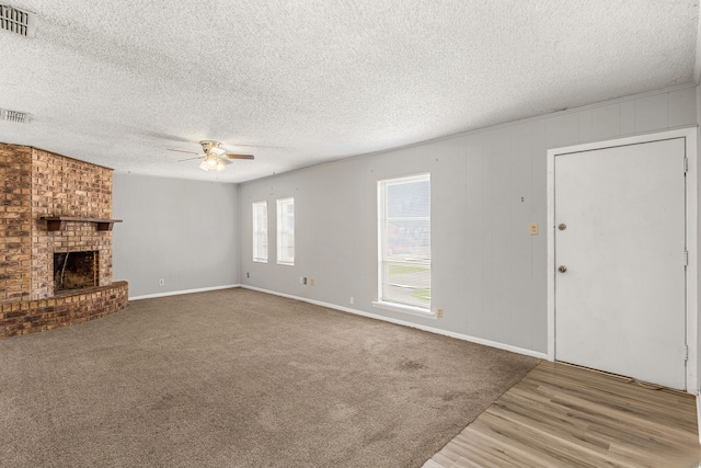 unfurnished living room featuring ceiling fan, a fireplace, light carpet, and a textured ceiling