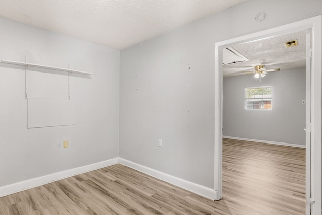 spare room featuring ceiling fan, light wood-type flooring, and a textured ceiling