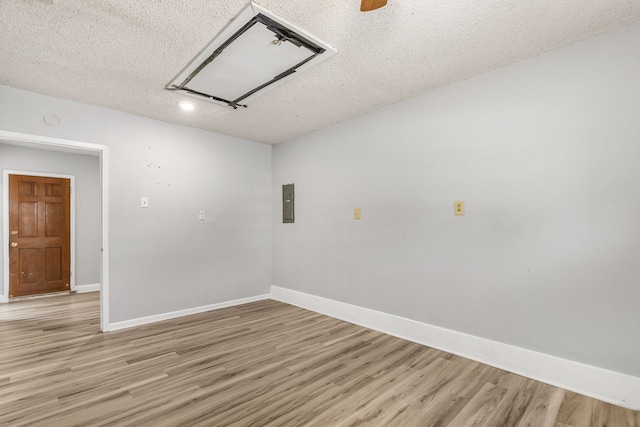 empty room with electric panel, a textured ceiling, and light hardwood / wood-style flooring