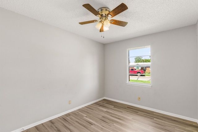 empty room featuring ceiling fan, light wood-type flooring, and a textured ceiling