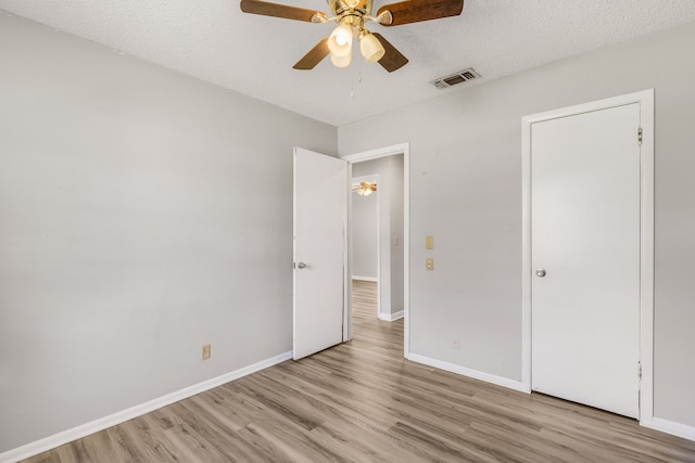 unfurnished bedroom with a textured ceiling, light hardwood / wood-style flooring, and ceiling fan