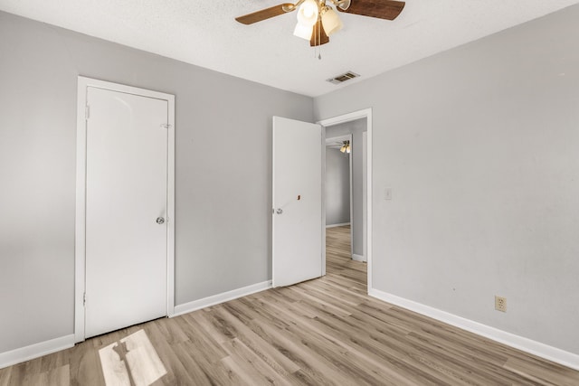 unfurnished bedroom featuring ceiling fan, a textured ceiling, and light wood-type flooring