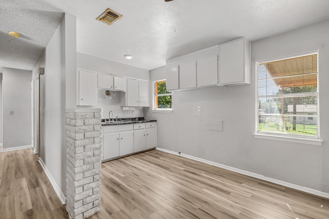 kitchen with sink, light hardwood / wood-style flooring, backsplash, a textured ceiling, and white cabinets