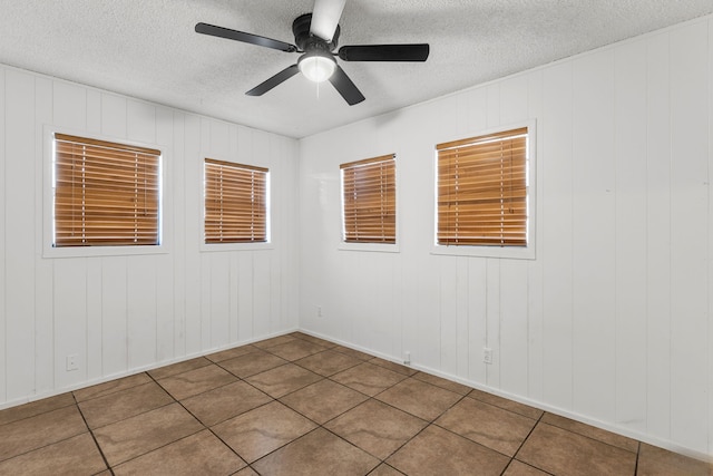 2920 Cunningham Dr, Wichita Falls, TX 76308 - tiled empty room with ceiling fan, a textured ceiling, and wood walls