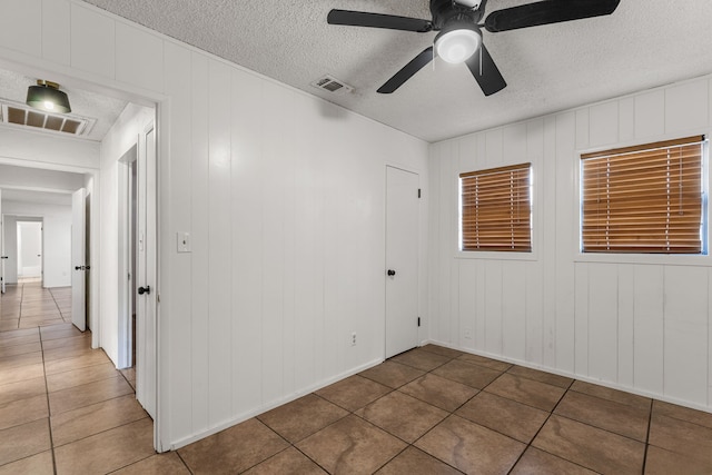 2920 Cunningham Dr, Wichita Falls, TX 76308 - tiled spare room featuring ceiling fan, a textured ceiling, and wood walls