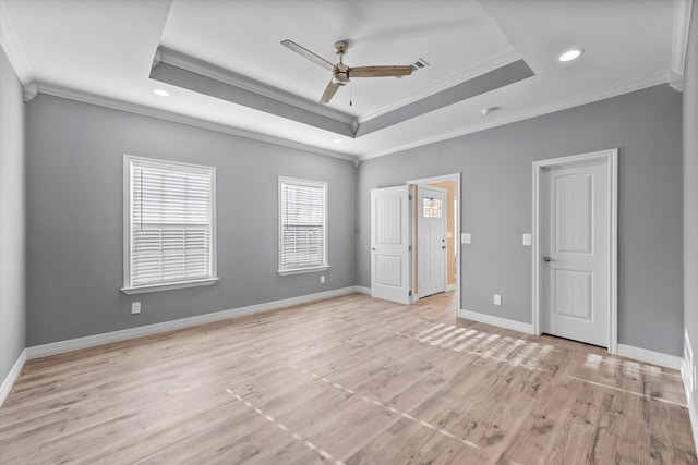 unfurnished bedroom featuring ceiling fan, ornamental molding, a raised ceiling, and light hardwood / wood-style flooring