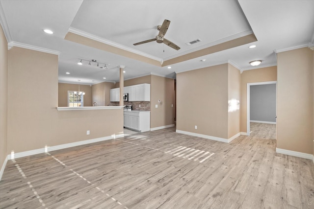 unfurnished living room with ceiling fan with notable chandelier, visible vents, baseboards, light wood-style floors, and a raised ceiling