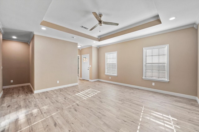 spare room with ceiling fan, ornamental molding, a raised ceiling, and light wood-type flooring