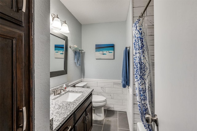 bathroom with toilet, a shower with curtain, tile walls, vanity, and tile patterned flooring