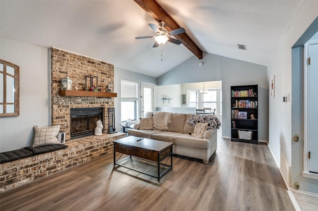 living room with hardwood / wood-style flooring, vaulted ceiling with beams, a textured ceiling, and a fireplace