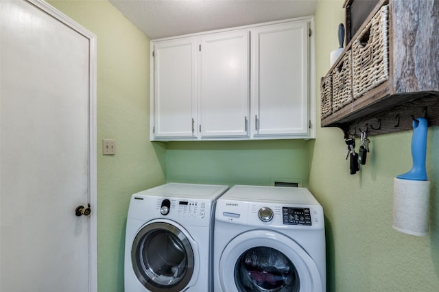 washroom featuring cabinets, washing machine and dryer, and a textured ceiling