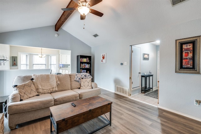 living room with ceiling fan with notable chandelier, light hardwood / wood-style floors, and vaulted ceiling with beams