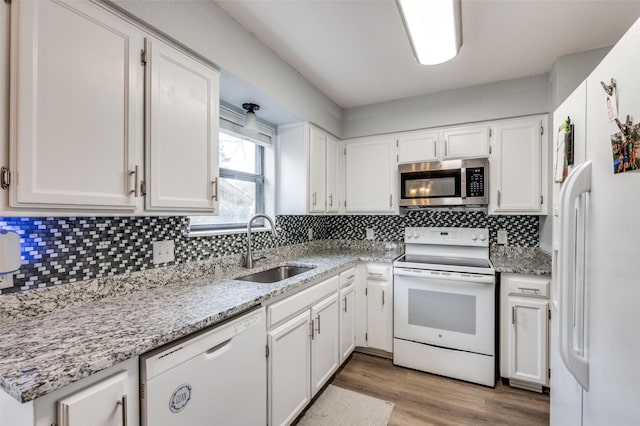 kitchen featuring sink, white appliances, white cabinetry, light stone countertops, and decorative backsplash