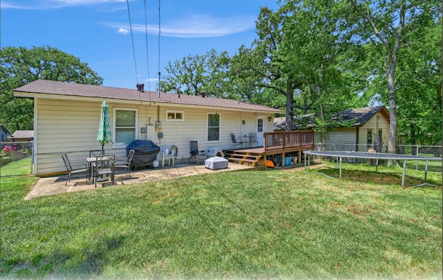 back of house with a patio, a deck, a yard, and a trampoline