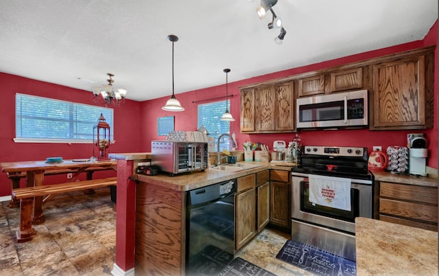 kitchen with pendant lighting, sink, appliances with stainless steel finishes, track lighting, and kitchen peninsula