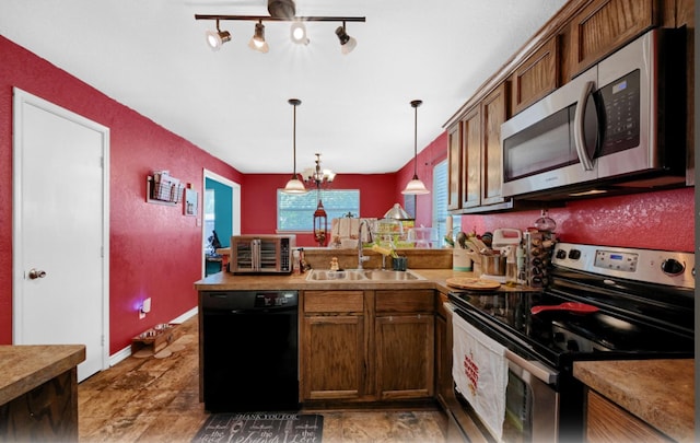 kitchen featuring sink, an inviting chandelier, track lighting, pendant lighting, and stainless steel appliances