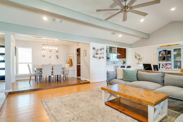 living room with lofted ceiling with beams, ceiling fan, sink, and light hardwood / wood-style floors