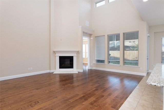 unfurnished living room with hardwood / wood-style flooring, plenty of natural light, and a towering ceiling