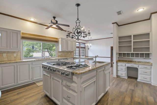 kitchen with pendant lighting, dark hardwood / wood-style floors, built in desk, stainless steel gas cooktop, and a kitchen island