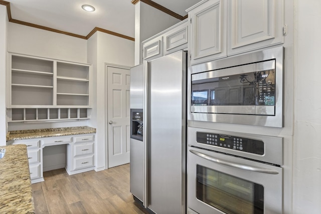 kitchen featuring crown molding, stainless steel appliances, light stone countertops, white cabinets, and light wood-type flooring