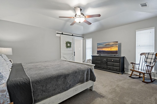 carpeted bedroom featuring ceiling fan and a barn door