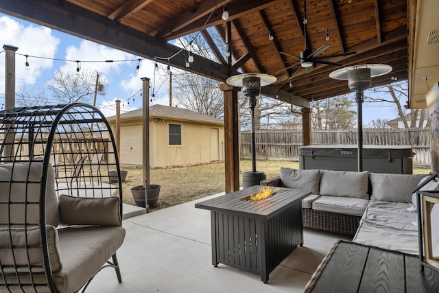 view of patio / terrace featuring an outbuilding, a hot tub, ceiling fan, and an outdoor fire pit