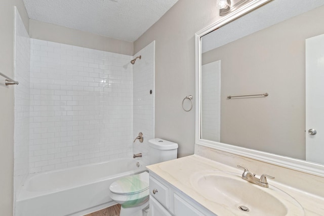 full bathroom featuring vanity, toilet, tiled shower / bath combo, and a textured ceiling