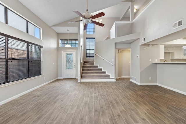 foyer entrance with hardwood / wood-style flooring, a towering ceiling, and ceiling fan