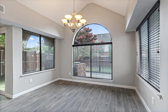 unfurnished dining area featuring lofted ceiling, a notable chandelier, and hardwood / wood-style floors