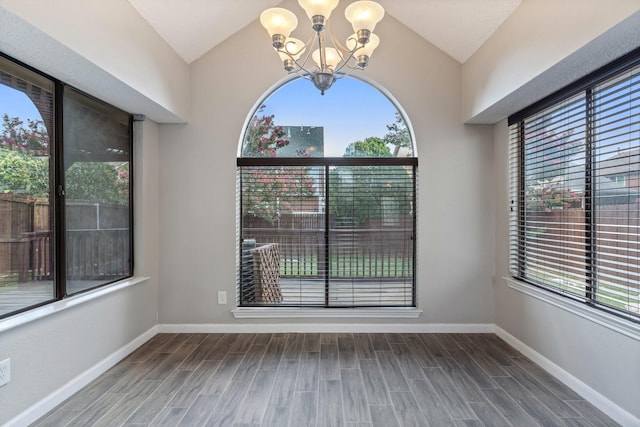 empty room featuring hardwood / wood-style flooring, vaulted ceiling, and a notable chandelier