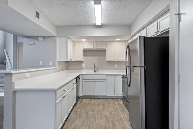 kitchen featuring sink, stainless steel refrigerator, dishwasher, white cabinets, and kitchen peninsula