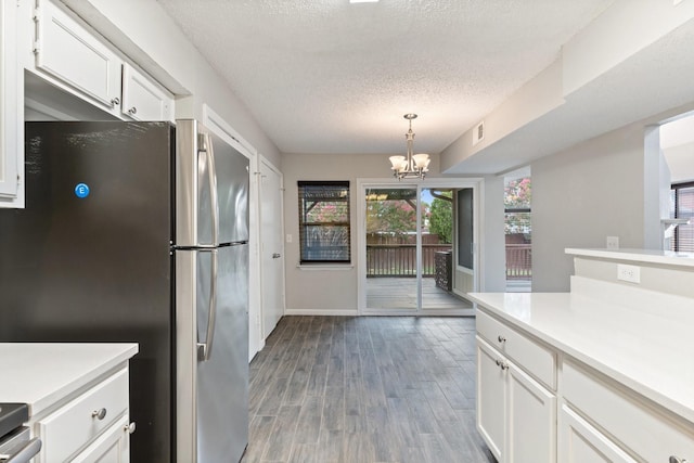 kitchen with white cabinetry, an inviting chandelier, a textured ceiling, stainless steel refrigerator, and pendant lighting