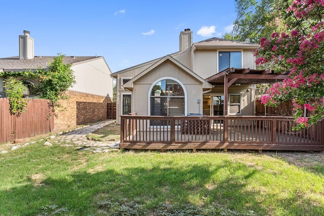 back of property with a pergola, a lawn, and a deck