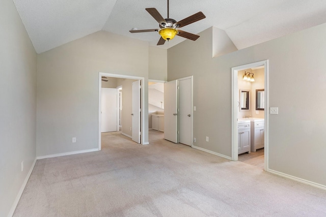 unfurnished bedroom featuring vaulted ceiling, sink, light colored carpet, ceiling fan, and ensuite bath