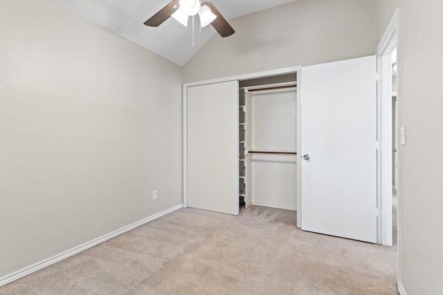 unfurnished bedroom featuring vaulted ceiling, light colored carpet, a closet, and ceiling fan