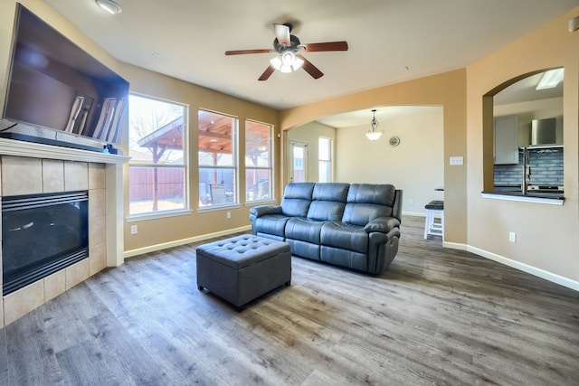 living room with a tiled fireplace, a healthy amount of sunlight, and hardwood / wood-style floors