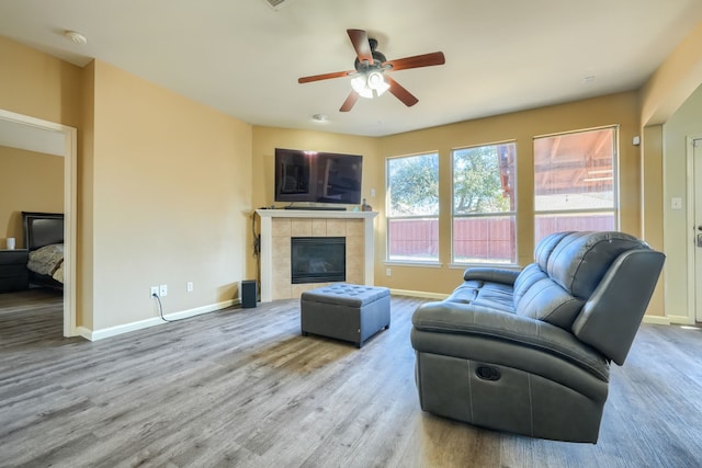 living room featuring a tile fireplace, ceiling fan, and light hardwood / wood-style flooring