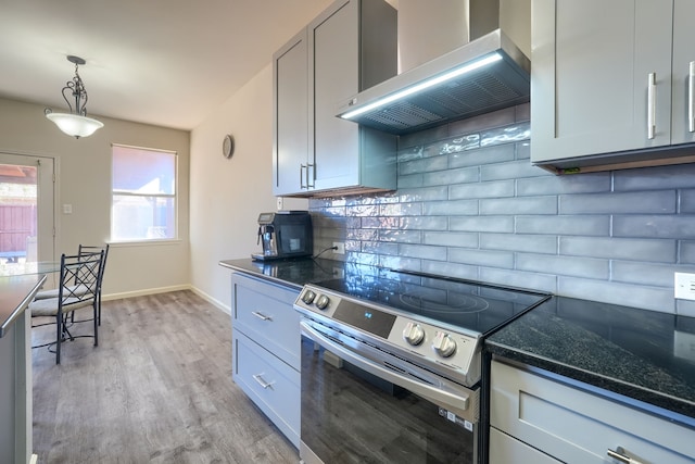 kitchen with light hardwood / wood-style flooring, pendant lighting, wall chimney range hood, stainless steel electric stove, and backsplash