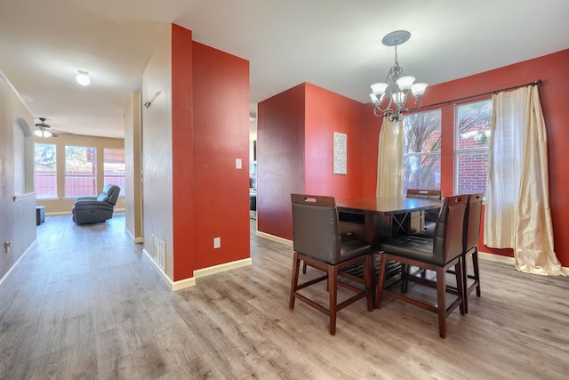 dining room with ceiling fan with notable chandelier and light hardwood / wood-style floors