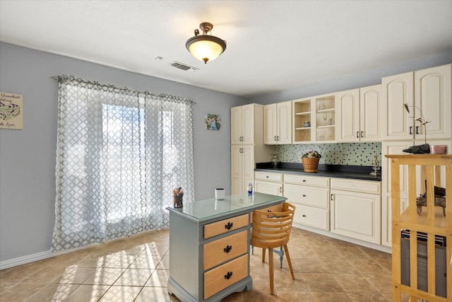 kitchen with light tile patterned flooring, a kitchen island, heating unit, decorative backsplash, and cream cabinetry