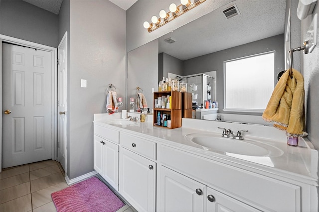 bathroom with walk in shower, vanity, tile patterned flooring, and a textured ceiling