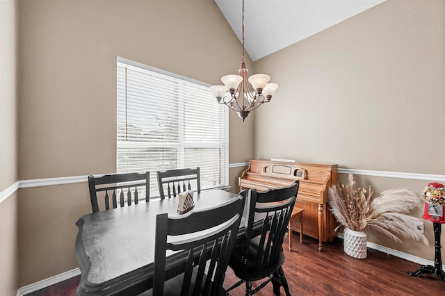 dining area with dark wood-type flooring, an inviting chandelier, and vaulted ceiling