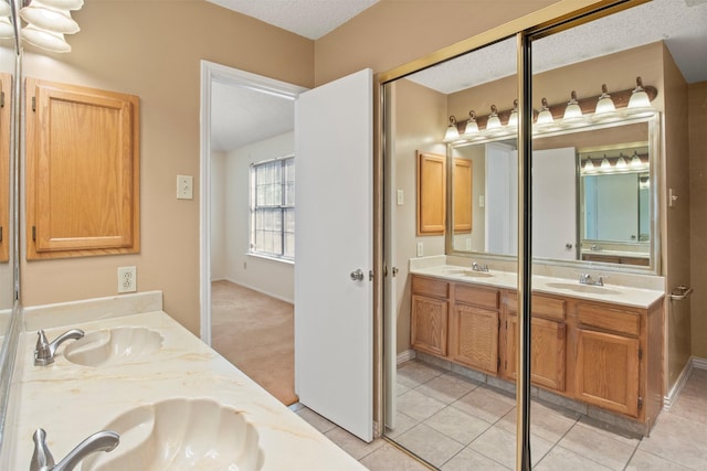 bathroom with tile patterned flooring, vanity, and a textured ceiling