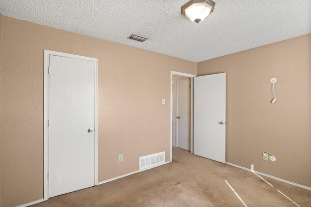 unfurnished bedroom with light colored carpet and a textured ceiling