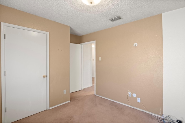 carpeted empty room featuring a textured ceiling